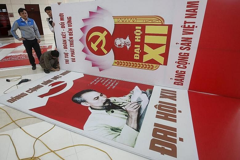Workers putting the finishing touches yesterday to posters bearing the Communist Party logo and images of late Vietnamese revolutionary leader Ho Chi Minh. Vietnam's Communist Party holds its 12th five-yearly national congress in Hanoi tomorrow.