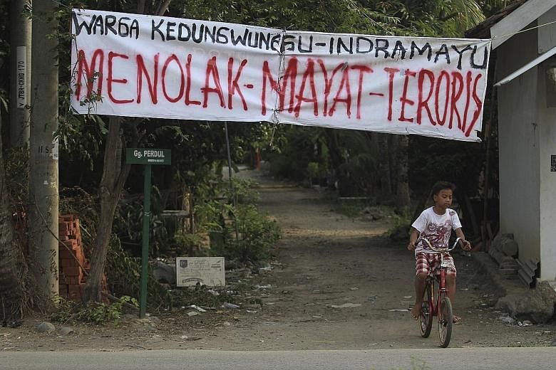A banner that reads "Reject Terrorist's Body" hanging over the entrance to Kedungwungu, home village of Ahmad Muhazin, one of the militants involved in last Thursday's terror attack in Jakarta.