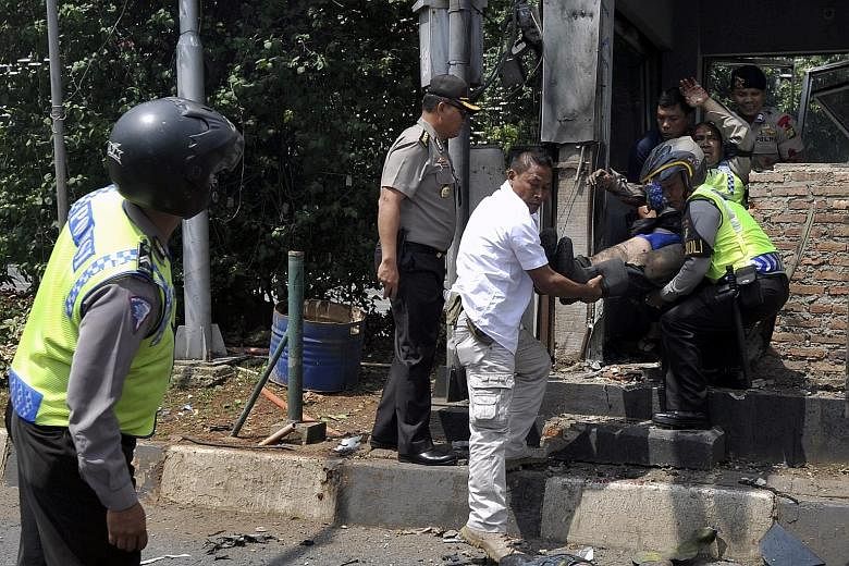 Indonesian police officers including Lt-Col Untung Sangaji (in white) evacuating an injured policeman after a bomb blast at a police post in front of a mall in Jakarta last Thursday. Lt-Col Untung told reporters yesterday he had no choice but to gun 
