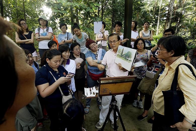 Mr Tham Pui San holding up a painting (left photo) and surrounded by participants (right photo) at the Singapore Botanic Gardens. The free sessions last two or three hours.