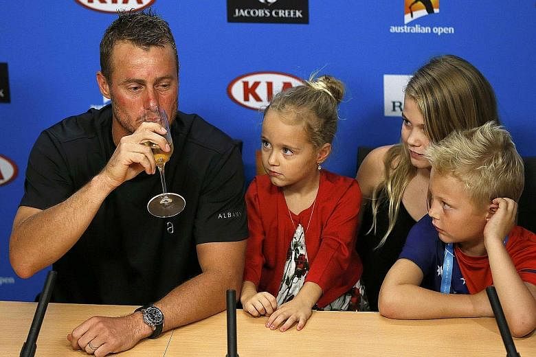 Australia's Lleyton Hewitt drinking champagne during a press conference after playing his last Australian Open match before his retirement. His children, (from left) Ava, Mia and Cruz, watch on.