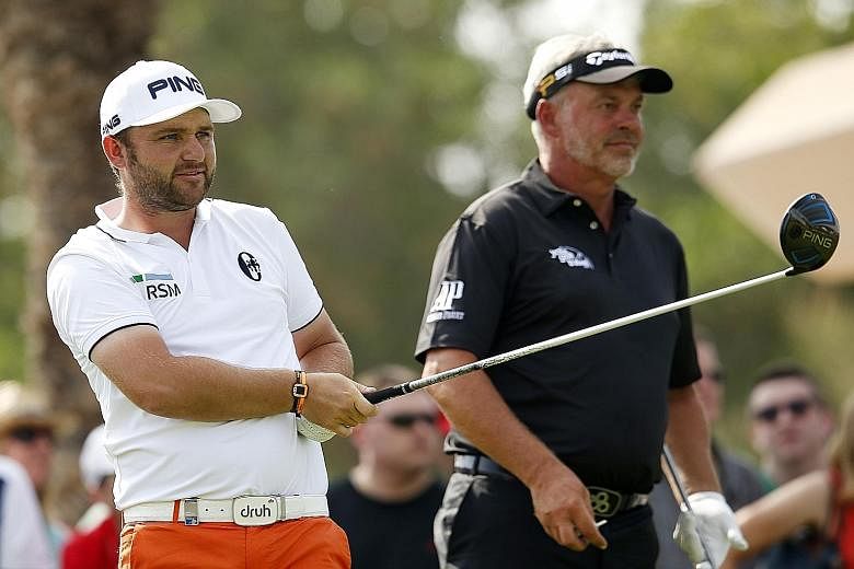 England's Andy Sullivan (left) teeing off at the 18th hole and being watched by Northern Ireland's Darren Clarke during the second round of the Abu Dhabi Championship.