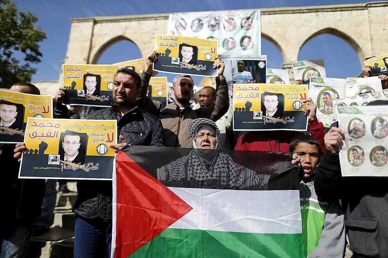 Palestinians with placards during a protest after Friday prayers in the compound known to Muslims as Noble Sanctuary and to Jews as Temple Mount in Jerusalem's Old City yesterday. The demonstrators were demanding the return of the bodies of those kil