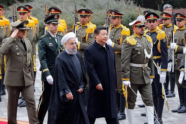 Iranian President Rouhani and his Chinese counterpart, Mr Xi, at a welcome ceremony at Iran's presidential palace in Teheran yesterday. Mr Xi is the first Chinese president to visit Iran in 14 years.