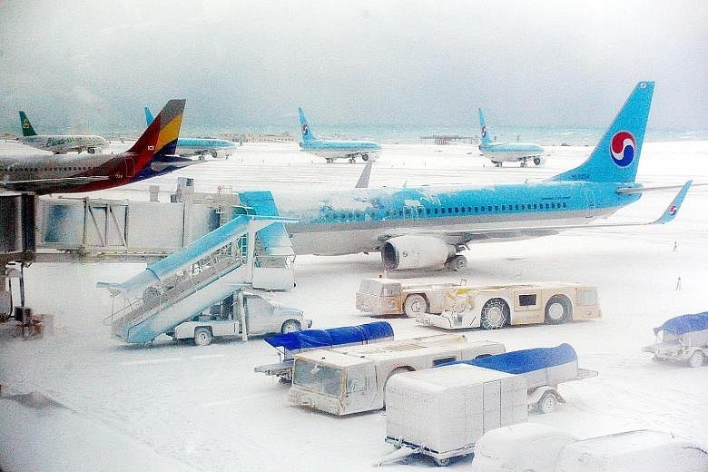 Planes on the snow-covered landing strip at Jeju International Airport. The island saw its biggest snowfall in three decades.