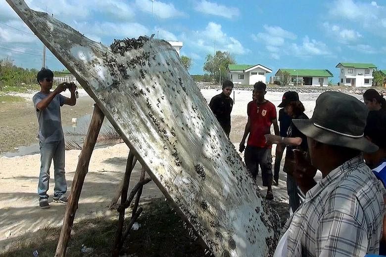Villagers inspecting the piece of suspected airplane wreckage at a beach in Nakhon Si Thammarat province, Thailand, on Saturday. Experts said while powerful currents sweeping the Indian Ocean could deposit debris thousands of kilometres away, wreckag