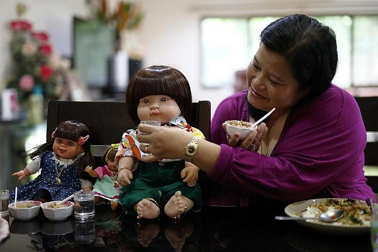 A Thai devotee feeding her child angel doll. Some Thais believe these dolls hold children's spirits, which bring good luck, wealth, blessing and protection from harm if they are well cared for.