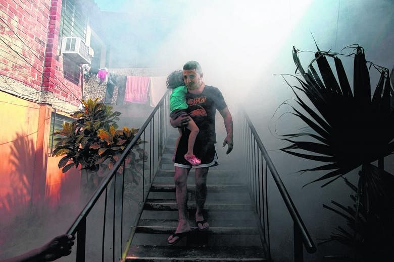 A man carrying his son away from his home as health workers fumigated the Altos del Cerro neighbourhood in El Salvador last week, as part of preventive measures against the Zika virus and other mosquito-borne diseases.