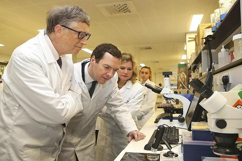 Microsoft co-founder Gates (at far left) with British Chancellor Osborne during their visit yesterday to the Liverpool School of Tropical Medicinein Britain.