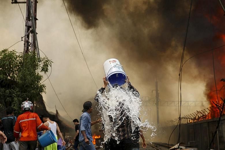 A man dousing himself with water during a fire in a slum area next to railway tracks in Kampung Muka, Kampung Bandan, North Jakarta, yesterday. According to local media, the fire destroyed about 100 wooden dwellings built along a busy railway line. A