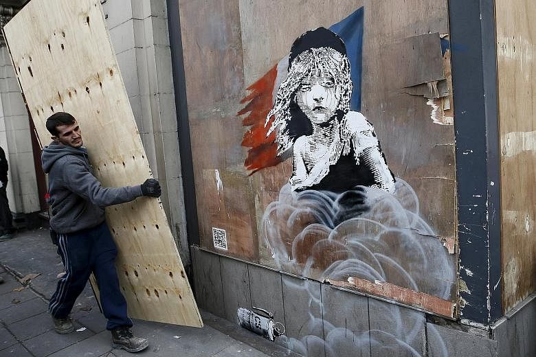 A worker about to cover a new mural, attributed to graffiti artist Banksy, opposite the French Embassy in London. The mural highlights the alleged use of tear gas on migrants at the "jungle" camp in Calais, and comes amid calls in Britain to take in 