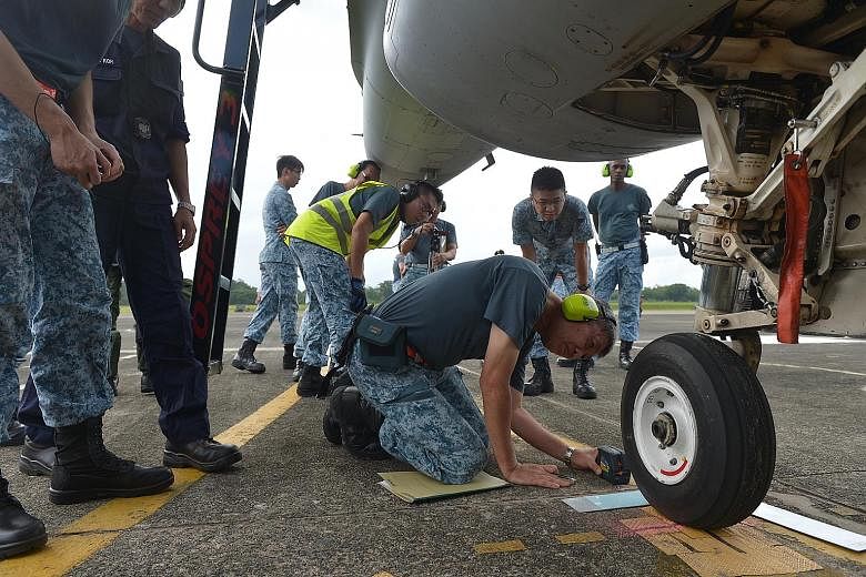 An assessor measures the accuracy of the precision marshaller in stopping the F-16 on its mark as the aircraft comes in to park at the Tengah Air Base after a mission.