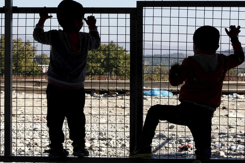 Two migrant children waiting for transport at a transit camp in Gevgelija, Macedonia, after entering the country. They had been taken across the border with Greece in November.