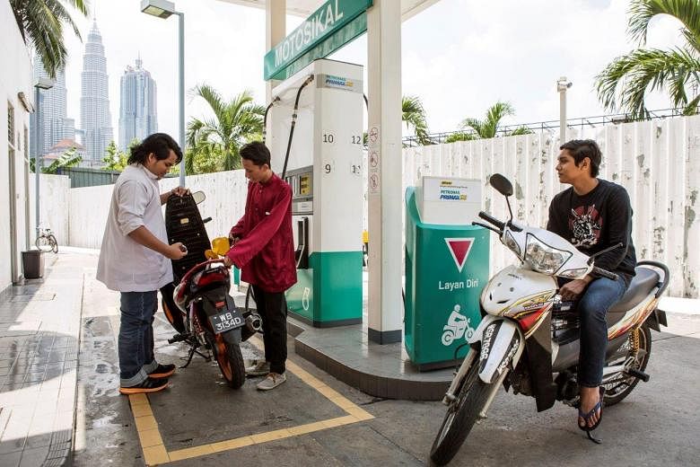 A customer refuelling his motorcycle at a Petronas station in Kuala Lumpur.