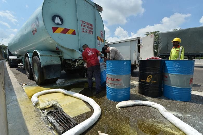 The clean-up crew trying to funnel the palm oil from the tanker into empty oil drums. Remnants of Friday's oil spill that caused a massive traffic jam on the Bukit Timah Expressway are still being cleared, with some pooling in a drain leading from the exp