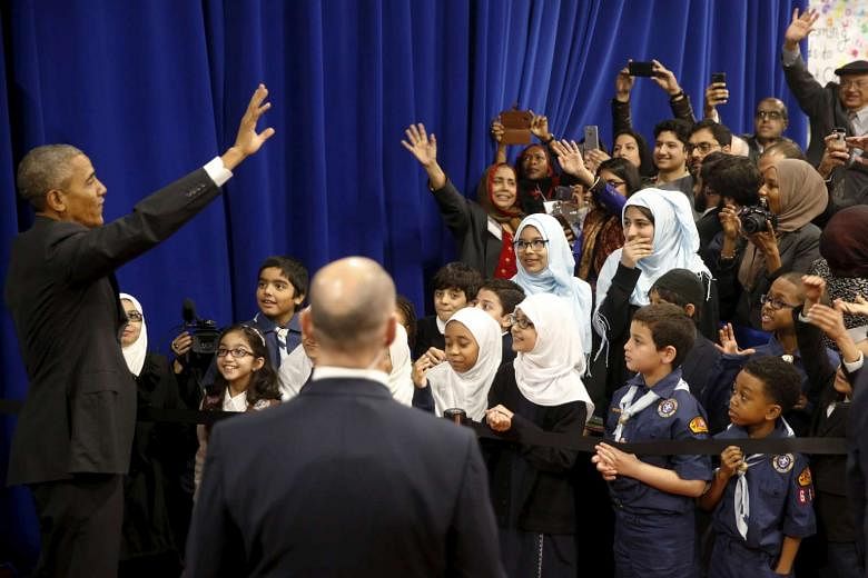 Mr Obama waves farewell to students after his remarks at the mosque in Maryland.
