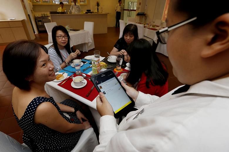Account executive Ms Chua having her order taken by a waiter using the colour-coded system. Each customer's place at a table is marked by a mat or coaster of a different colour. Waiters then take orders using a tablet that locks in the customer's order ba