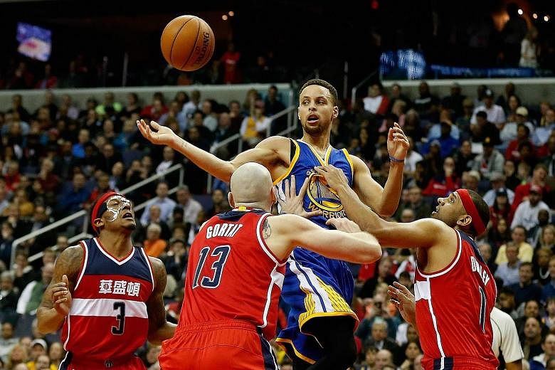 Stephen Curry of the Golden State Warriors passing the ball while being guarded tightly by Washington Wizards players.