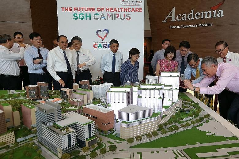 Prime Minister Lee Hsien Loong (right) and Health Minister Gan Kim Yong snapping photos of a model of SGH's campus masterplan yesterday. With them is Senior Minister of State for Health Amy Khor (in pink). More space will be given to areas where the 