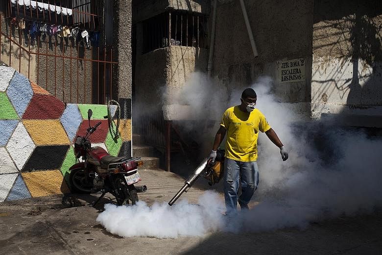 A worker in a neighbourhood in Venezuela's capital, Caracas, spraying insecticide on Wednesday to eradicate mosquitoes. Mosquito-eating sambo fish are being put in home water tanks as one of El Salvador's biological methods to control the insect's po