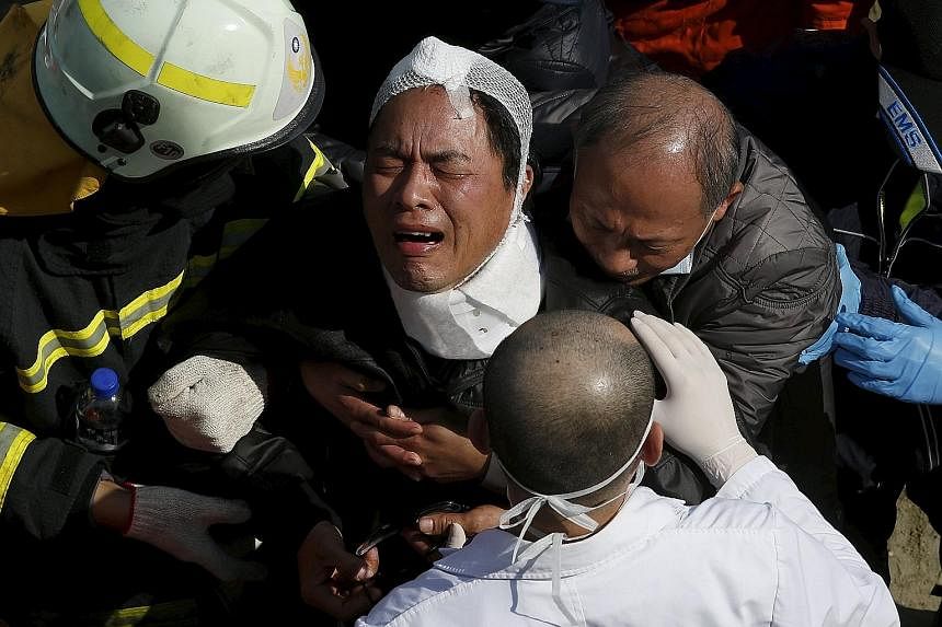 Left: Rescuers searching for survivors following the earthquake in Tainan city. Officials said a probe has been launched as questions have been raised over the safety of the building complex. Below: A man grieving after a family member was confirmed 