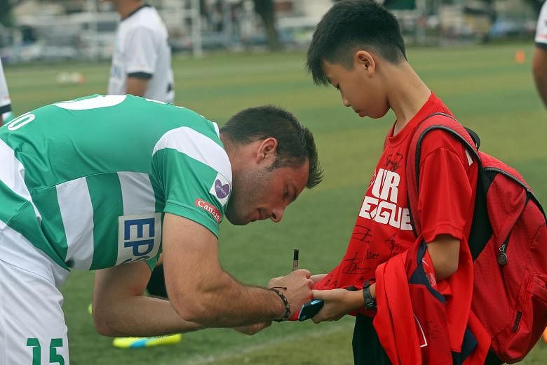 Geylang's Croatian forward Branko Cubrilo (above) signs an autograph for fan Bryan Lee during a meet-and-greet session yesterday. 0n the same pitch, Geylang's new adviser, MP Tin Pei Ling (left), takes on club defender Al-Qassimy Rahman during a kick-abou