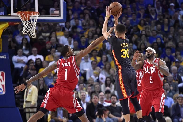 The Golden State Warriors' Stephen Curry shooting a three-pointer with the Houston Rockets' forward Trevor Ariza and centre Josh Smith defending. The point guard scored 35 points and the Warriors outlasted James Harden's game-high 37 to beat the Rockets 1