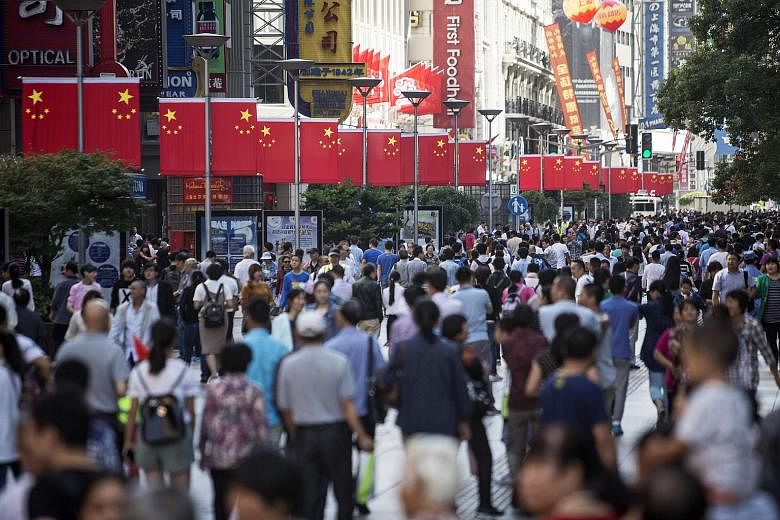 Pedestrians walk past Chinese national flags displayed along the Nanjing Road pedestrian street in Shanghai. 