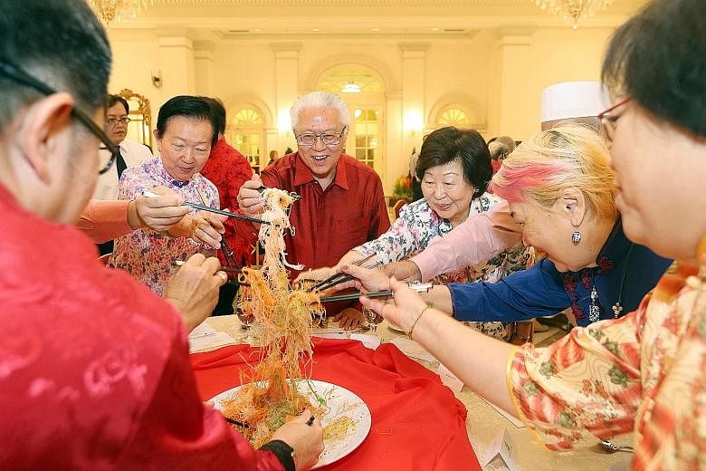 President Tan and Mrs Mary Tan tossing yusheng with seniors like Ms Chong (on President Tan's right), and Reach volunteers and staff.