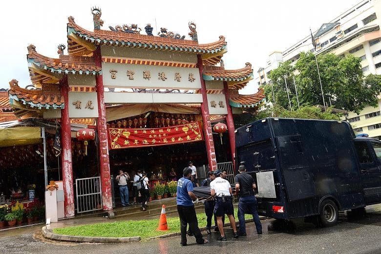 Police officers and undertakers removing the body of Mr Tan Poh Huat from the temple in Teck Whye Lane on Sunday. The victim's sister, Madam Tan Sui Kee, believes her brother had been carrying more than $10,000, as people had seen him exchanging note