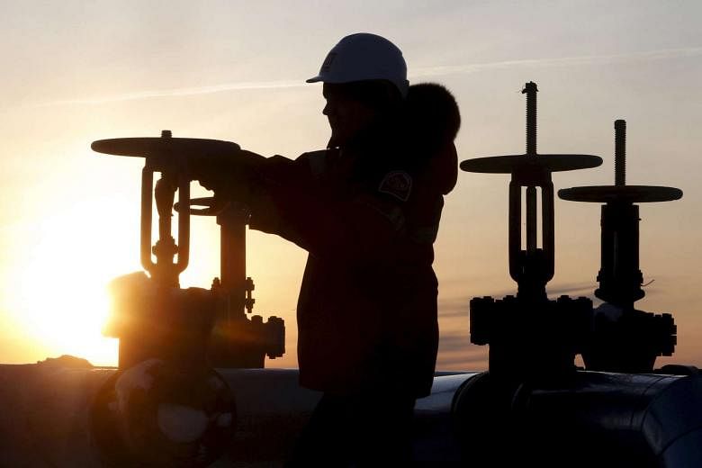 A worker checks the valve of an oil pipe at the Lukoil-owned Imilorskoye oil field in Russia. 