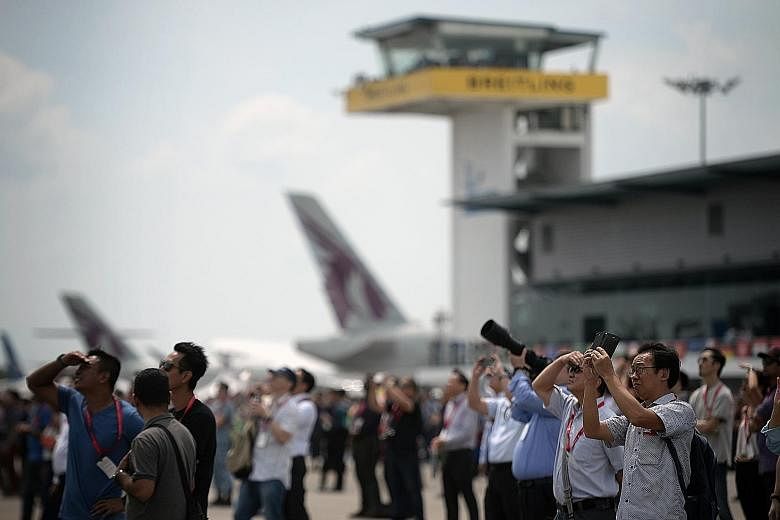 Singapore Airshow visitors watching an aerobatic flying display yesterday. On Tuesday, visitors were left waiting for over an hour to get a taxi. Experia Events said it had alleviated the situation by increasing the frequency of shuttle bus services 