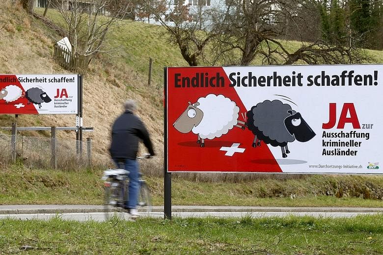 Posters put up by the Swiss People's Party are displayed on a road in Adliswil, Switzerland. The posters read: "At last make things safer! Say yes to deportation of criminal foreigners." Those opposed to the anti-immigration party's referendum campai