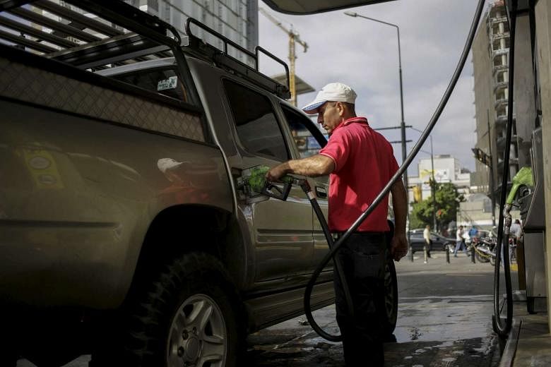 A worker pumps gas into a vehicle at a gas station that belongs to Venezuela's state oil company PDVSA in Caracas.