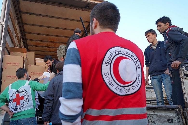 The Syrian Arab Red Crescent and the International Committee of the Red Cross distributing food aid in a buffer zone on the edge of Moadamiyeh, a city under siege in Syria, earlier this month.