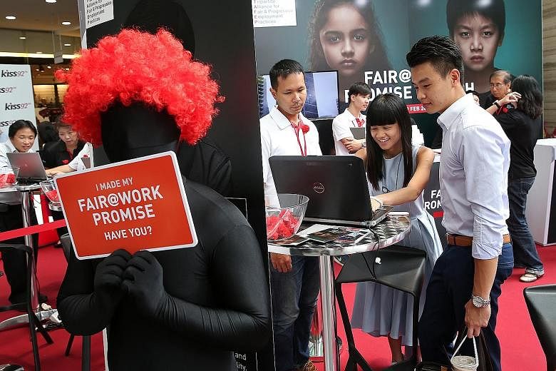 Accountants Michelle Ling, 27, and Jeffrey Chen, 26 (right), making their personal commitment on the Fair@Work Promise microsite during the launch of the initiative at Chevron House yesterday.