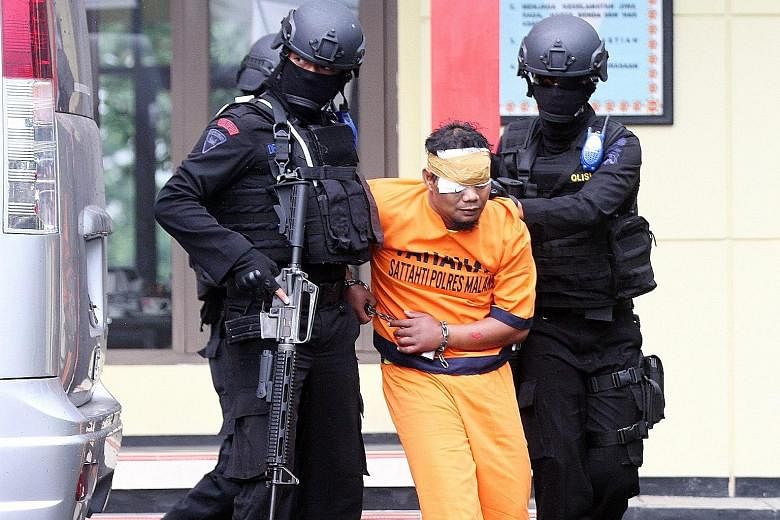 Officers from Indonesia's counter-terror unit escorting a terror suspect at a police station in Malang, East Java, yesterday. At least one of the six men arrested was directly linked to the four militants who mounted the attack in Jakarta on Jan 14. 