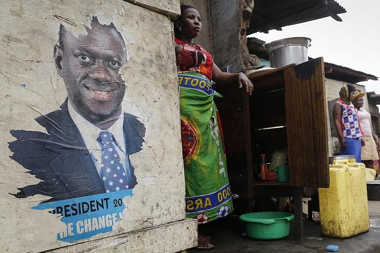 Stallholders in Kampala, Uganda, awaiting the results of the presidential election last Saturday. President Yoweri Museveni beat seven rivals, including opposition leader Kizza Besigye (pictured in poster) to win his fifth term.