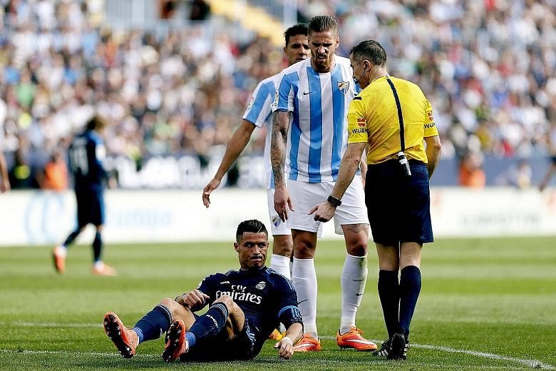 Cristiano Ronaldo after being knocked down by Malaga's Raul Albentosa (centre) during the 1-1 La Liga draw on Sunday.