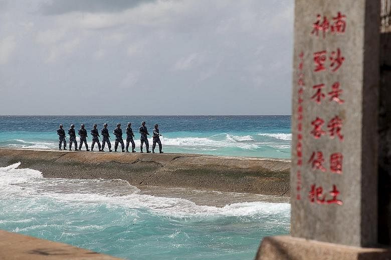Above: Soldiers from China's People's Liberation Army on patrol in the Spratly Islands, known in China as Nansha Islands, earlier this month. The sign reads "Nansha is our national land, sacred and inviolable". Images from a US think-tank appear to s