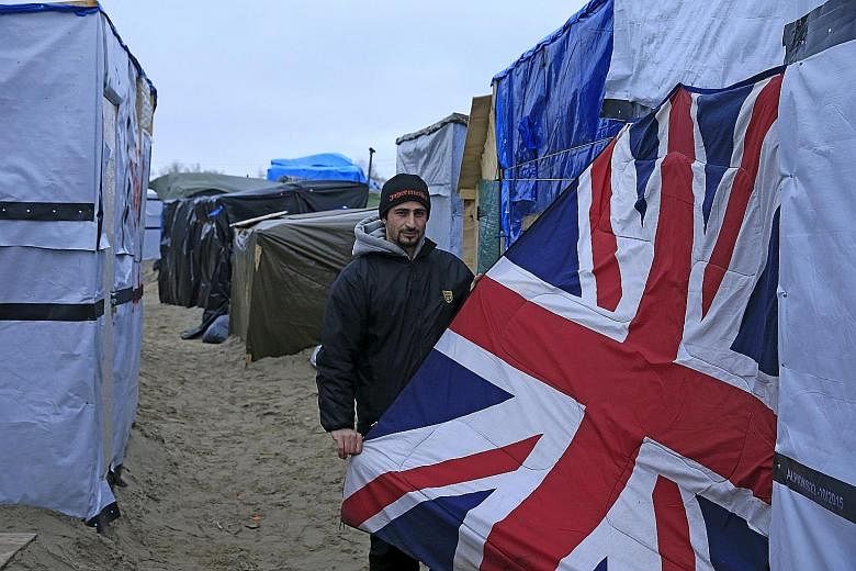 A Syrian migrant with a Union Jack covering used as a door to his shelter in the "Jungle" camp in Calais. The French authorities plan to demolish half of the camp but its inhabitants are resisting an eviction order.