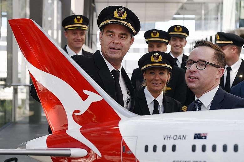 Qantas CEO Alan Joyce (right in photo) chatting with pilots after announcing the airlines' first-half net profit of 234 per cent at a media briefing in Sydney, Australia, yesterday.