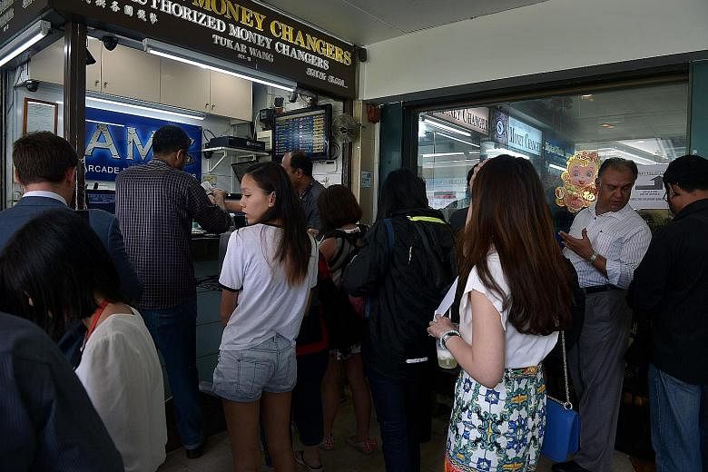 Customers queueing at a money changer in Raffles Place on Tuesday. Britain's pound slid for a third day yesterday, touching 1.9568 Singdollars, its lowest level since June 2013.