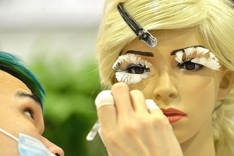 Eyelash master Andy Tiang Zhi Pink, 23, from Andy Chang Beauty Station in Kuala Lumpur, putting feather eyelashes on a mannequin at the BeautyAsia 2016 trade exhibition at Suntec Singapore yesterday. Mr Tiang won the first prize in the Artistic Eyela