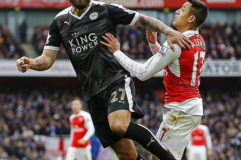 Leicester's Marcin Wasilewski beating Arsenal's Alexis Sanchez to the ball in their 1-2 loss. Despite the setback, the Foxes lead by two points and will be in pole position for the title run-in if they win the next five games.