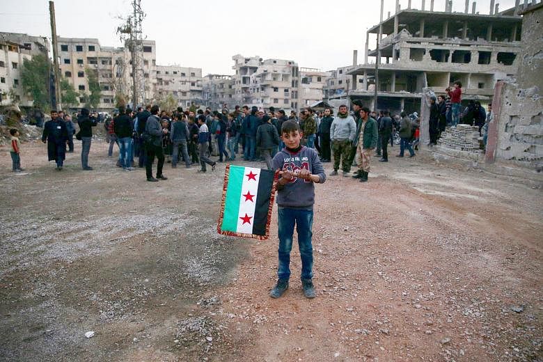 A boy carries an opposition flag in the rebel-held town of Kafr Batna. The Syrian Observatory for Human Rights said Russia and the regime yesterday launched a wave of attacks on rebel areas ahead of the ceasefire deadline. 