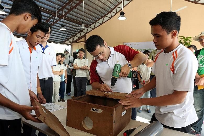 Mr Desmond Lee (third from left), Senior Minister of State for Home Affairs and National Development, watching ITE College East students build a nesting box for blue-throated bee-eaters at the Ubin Learning Lab yesterday.