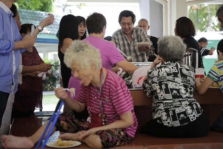 Mr Tan Cheng Tey serving food prepared by his wife and himself, as well as his church, to needy residents from the Chai Chee area yesterday. Since late last year, Mr Tan has been serving meals at the void deck of his block so as to interact more with