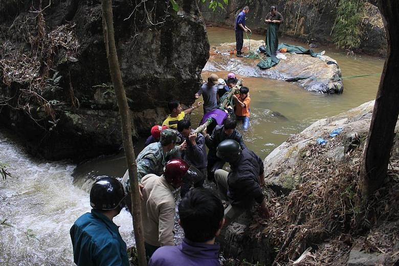Rescuers with the body of one of three British tourists who died after falling into a waterfall on the outskirts of the central highland town of Dalat in Vietnam on Friday. It is believed that one of them slipped and inadvertently dragged the others 