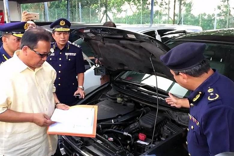 Datuk Seri Ismail Ahmad, director-general of Malaysia's Road Transport Department, last Friday inspecting "cloned" cars brought in from Singapore, which were later given new chassis numbers and sold in Malaysia.